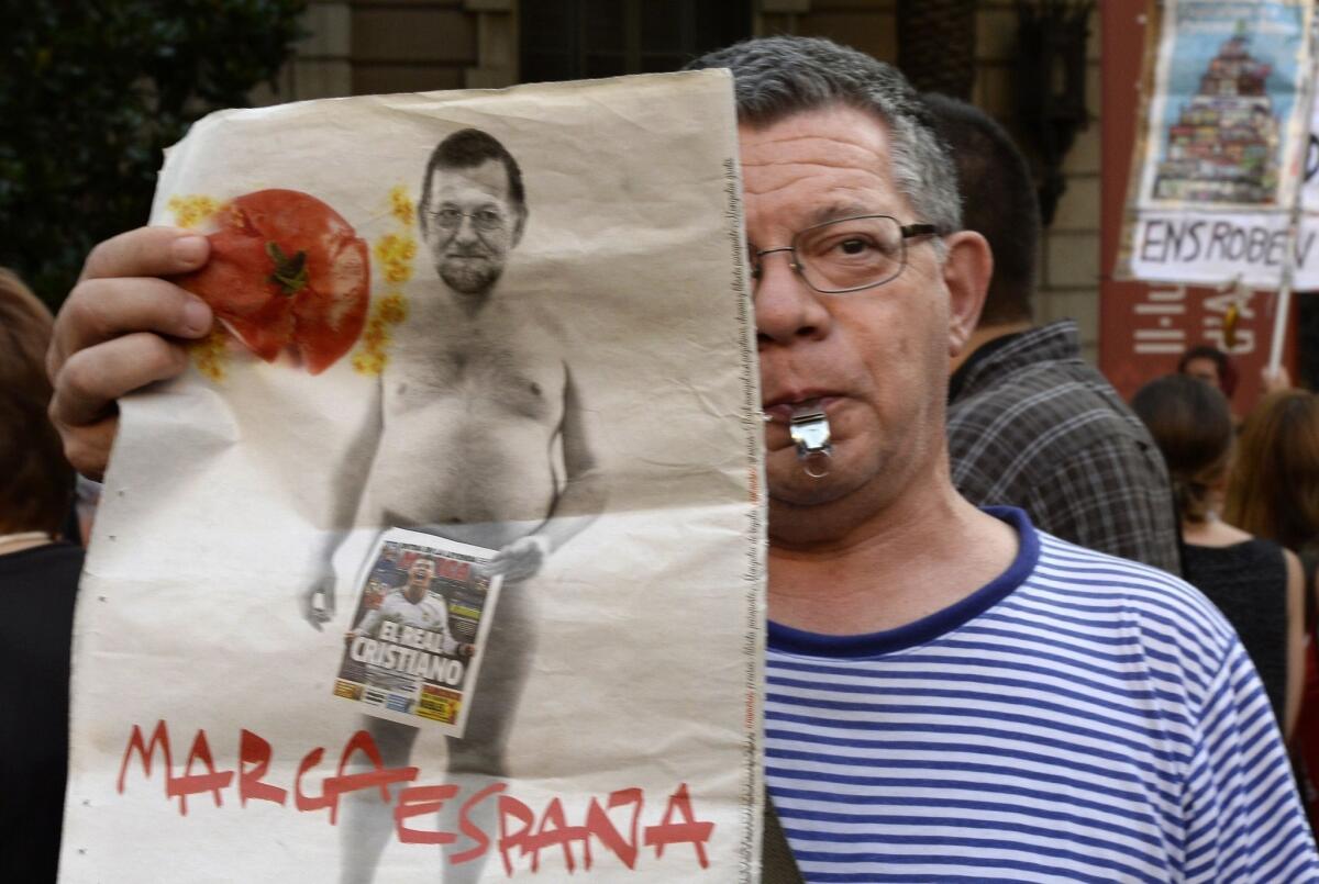 A protester holds a placard depicting Spanish Prime Minister Mariano Rajoy during a demonstration against corruption outside the Popular Party's headquarters in Barcelona.