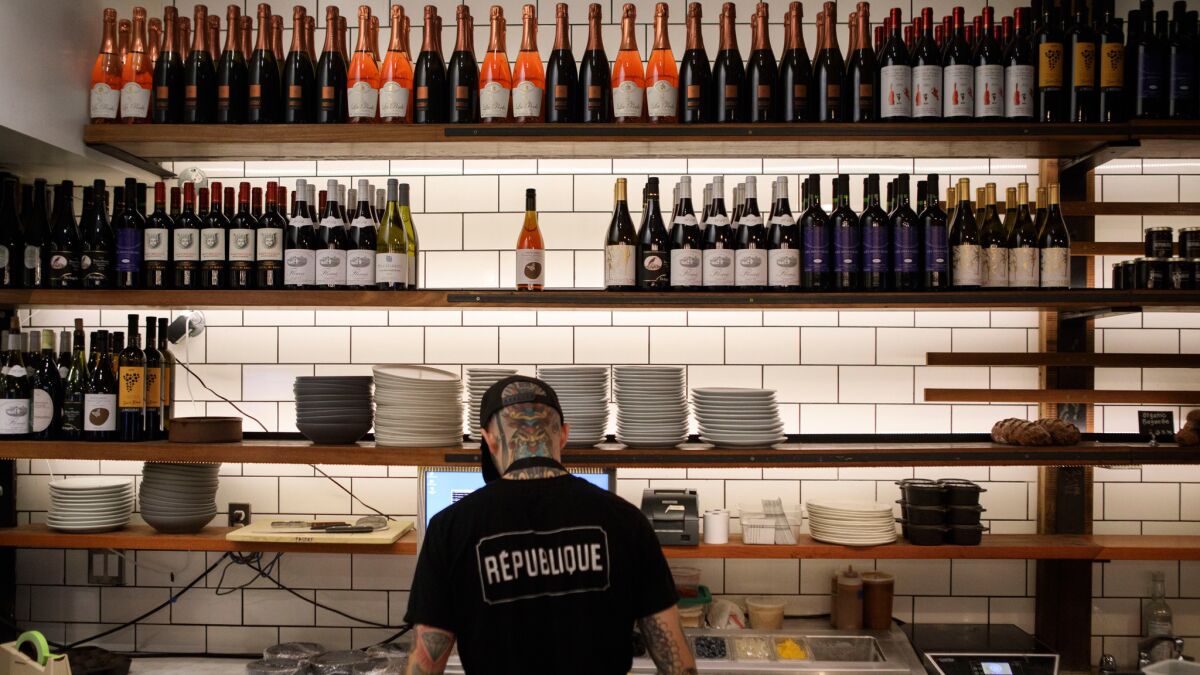 An employee prepares food as bottles of wine stand on shelves at Republique restaurant.
