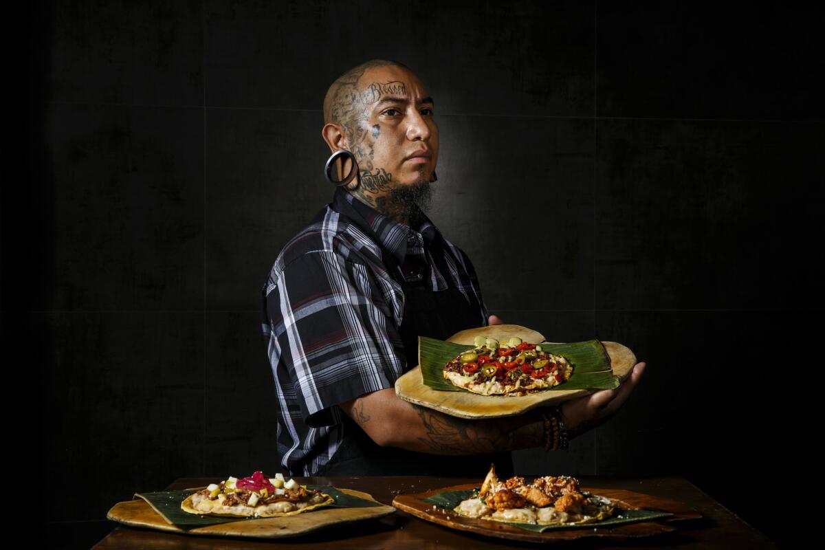 Chef Eddie Garcia holds up "Tlayuda de Chorizo y Chapulines," with crispy chorizo and toasted crickets, at Cocina Condesa.