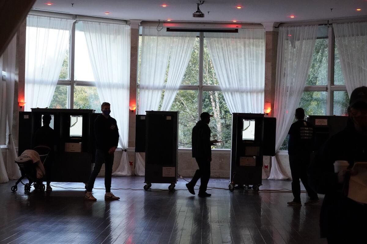 People in a room with voting booths.