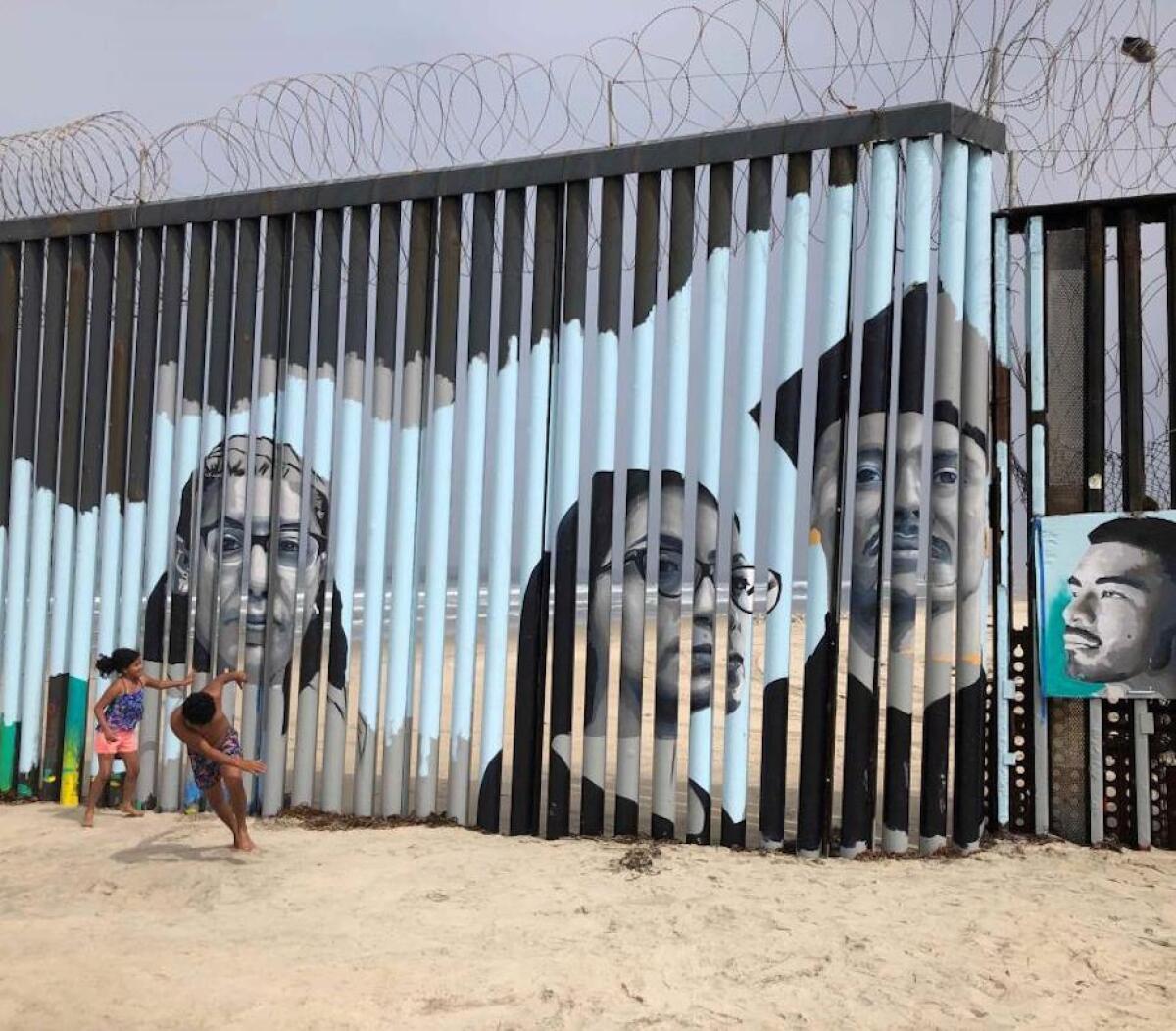 Dos niños juegan frente a un nuevo mural en el lado mexicano del muro fronterizo en Tijuana, México,