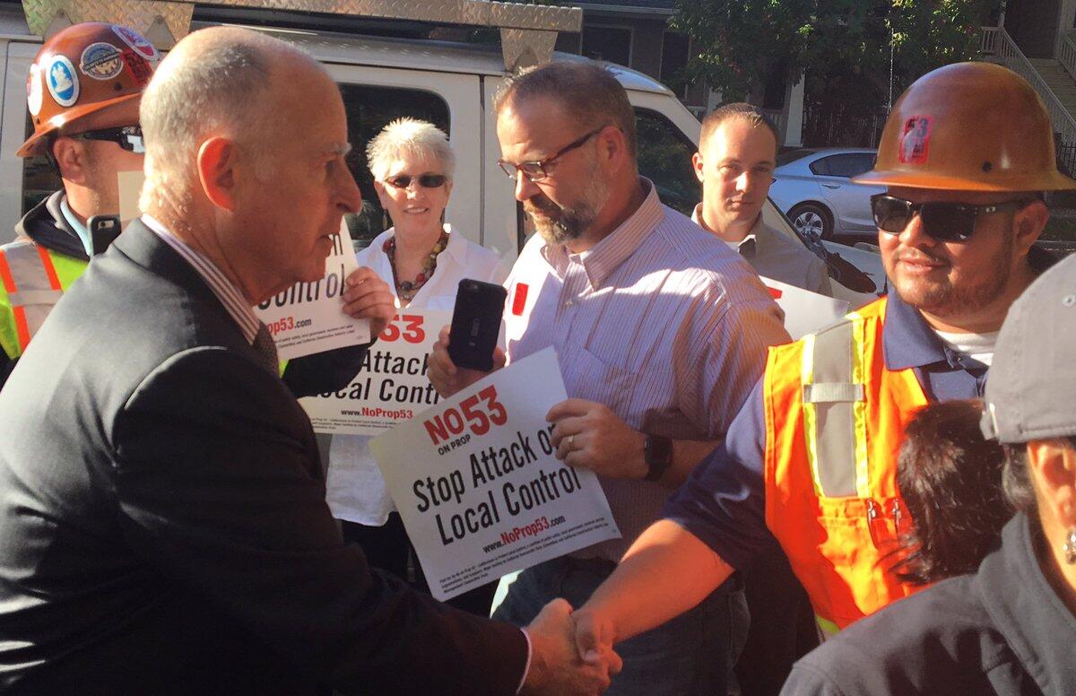 Gov. Jerry Brown greets workers outside his Sacramento polling place on Tuesday.