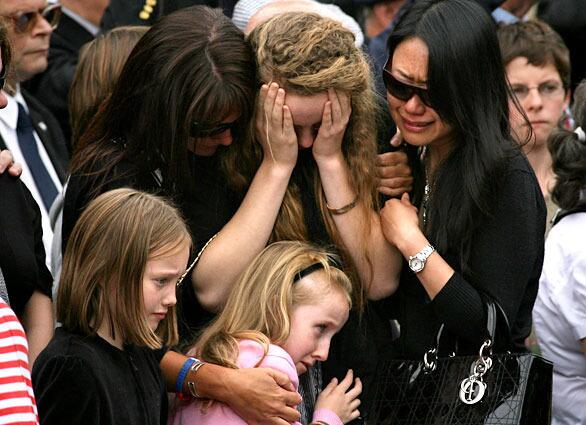 WOOTTON BASSETT, ENGLAND - AUGUST 18: The daughters of Captain Mark Hale, Tori (top centre) and Alex (bottom centre) are comforted by friends and family as the hearses carrying the coffins of Lance Bombardier Matthew Hatton, 23, Rifleman Daniel Wild, 19, and their father Captain Mark Hale, 42, pass mourners lining the High Street on August 18, 2009 in Wootton Bassett, England. The repatriation to the nearby RAF Lyneham of the bodies of two soldiers and the comrade they died trying to save, is the first since fatalities in Afghanistan passed the 200 mark. Three further soldiers, from 2nd Battalion The Royal Regiment of Fusiliers were killed while on patrol near Sangin on Sunday, bringing the total number of casulties since operations began in 2001 to 204 with the recent rise in numbers largely attributed to Operation Panther's Claw - a surge against the Taliban in central Helman. (Photo by Matt Cardy/Getty Images)