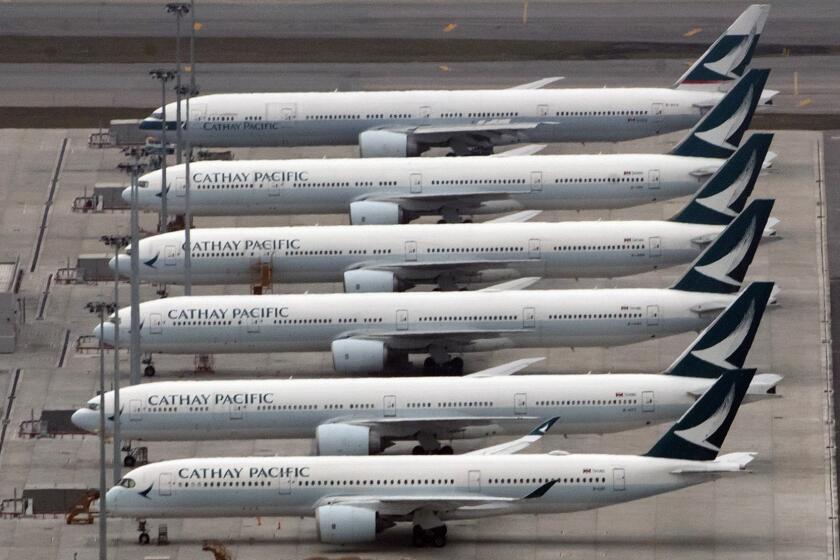 FILE - In this March 6, 2020, file photo, Cathay Pacific aircrafts line up on the tarmac at the Hong Kong International Airport. President Donald Trump has repeatedly credited his February ban on travelers from mainland China as his signature move against the advance of the coronavirus pandemic -- a “strong wall” that allowed only U.S. citizens inside, he boasted in May. But Trump’s wall was more like a sieve. Exempted were thousands of residents of the Chinese territories of Hong Kong and Macau. (AP Photo/Kin Cheung, File)