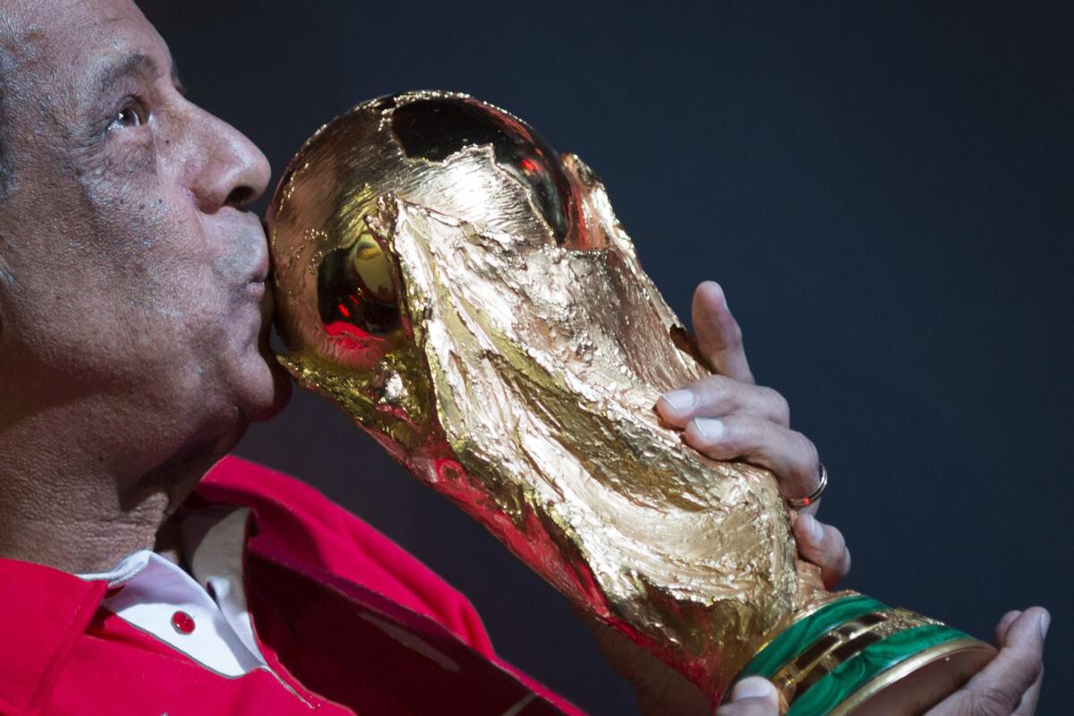 Former Brazilian soccer captain Carlos Alberto Torres kisses the World Cup trophy at the Maracana Stadium in Rio de Janeiro on April 22, 2014.