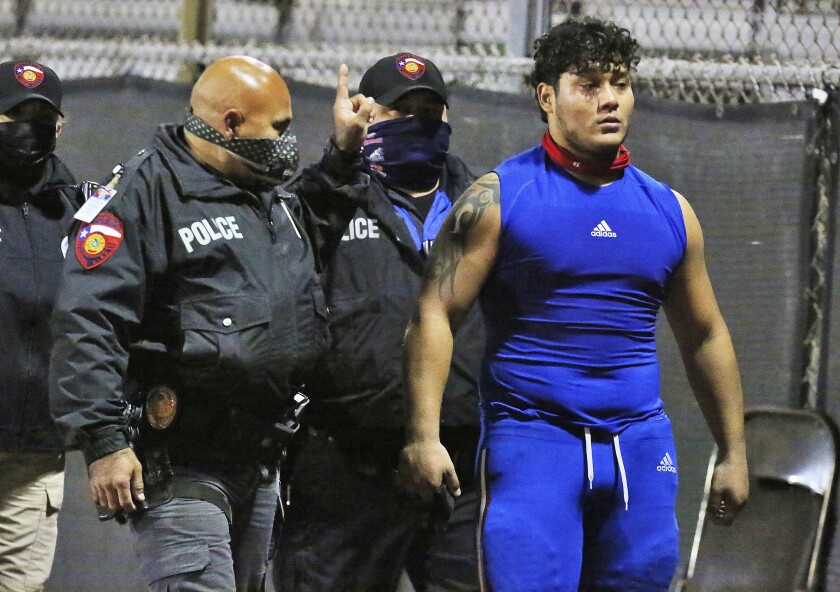 Edinburg's Emmanuel Duron is escorted out of the stadium by police after charging a referee during a high school football zone play-in game against Pharr-San Juan-Alamo on Thursday, Dec. 3, 2020, in Edinburg, Texas. (Joel Martinez/The Monitor via AP)