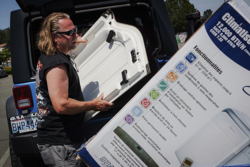 Brian Gadzuk, 56, clears out the trunk of his Jeep to make space for a new air conditioning unit in the parking lot of McLendon Hardware in Renton, Wash., on Sunday, July 24, 2022. The Pacific Northwest is bracing for a major heat wave, with temperatures forecast to top 100 degrees Fahrenheit (37.8 Celsius) in some places this week as climate change fuels longer hot spells in a region where such events were historically uncommon. (Kori Suzuki/The Seattle Times via AP)