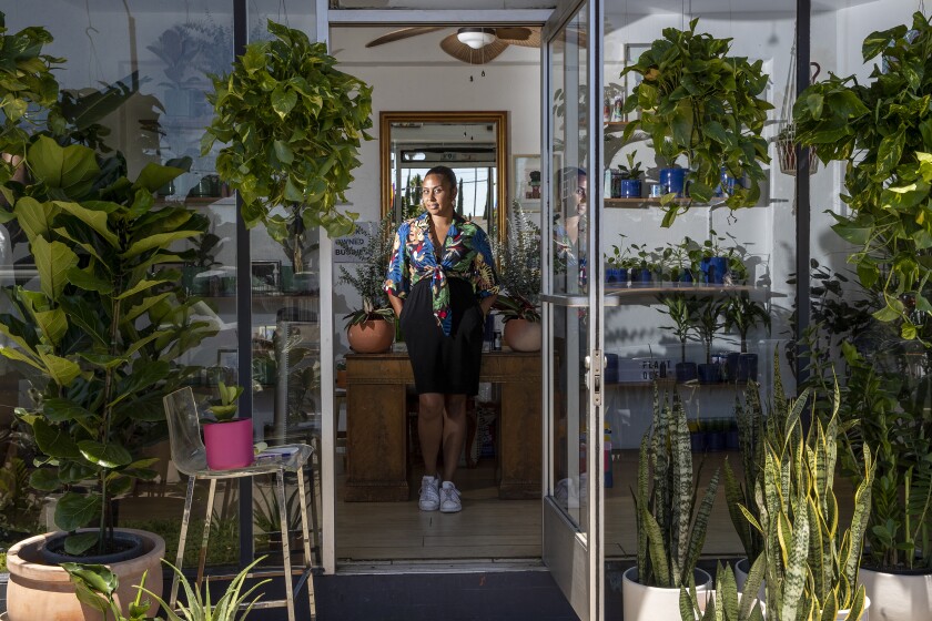 A woman is seen through a shop doorway surrounded by plants