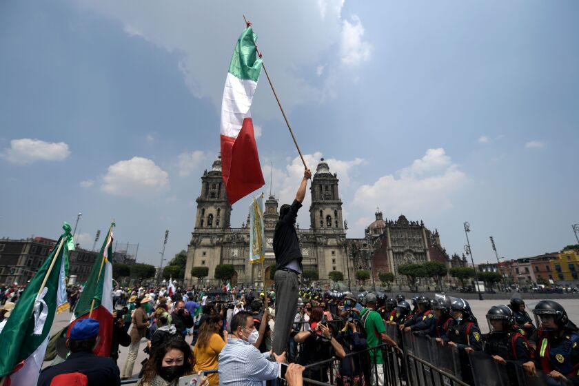 A member of the National Front Anti-AMLO (Frena) holds up a Mexican flag in front of a line of riot police during a protest against Mexican President Andres Manuel Lopez Obrador (ALMO) at the Zocalo Square in Mexico City on September 23, 2020, amid the COVID-19 novel coronavirus pandemic. (Photo by PEDRO PARDO / AFP) (Photo by PEDRO PARDO/AFP via Getty Images)