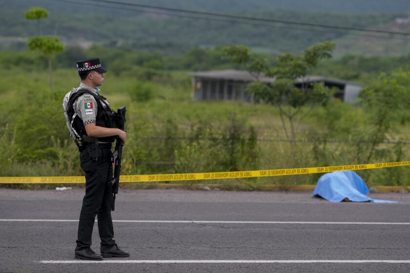 Un miembro de la Guardia Nacional vigila una carretera cerca de donde yace un cadáver en Culiacán, Sinaloa, en el norte de México, el sábado 21 de septiembre de 2024. (AP Foto/Eduardo Verdugo)