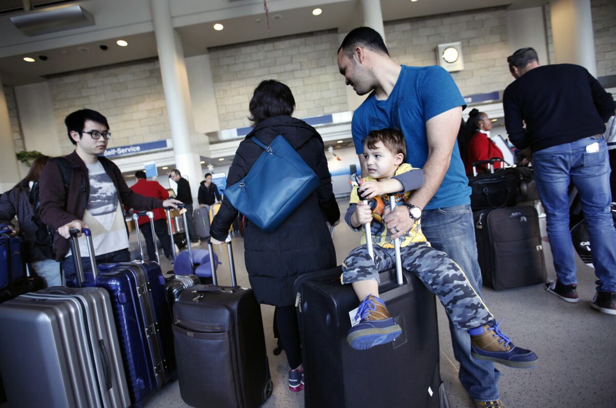 Idan Madhala and his son Daniel, 2, wait for a flight at Los Angeles International Airport on Dec. 24, 2014.