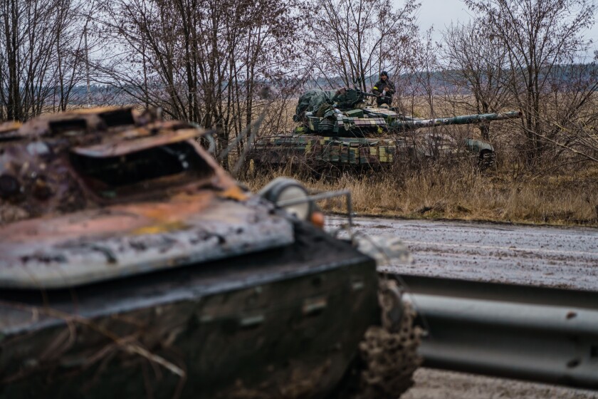 A Ukrainian tank driver stand ready on a tank in a ready position on a highway near Sytnyaky