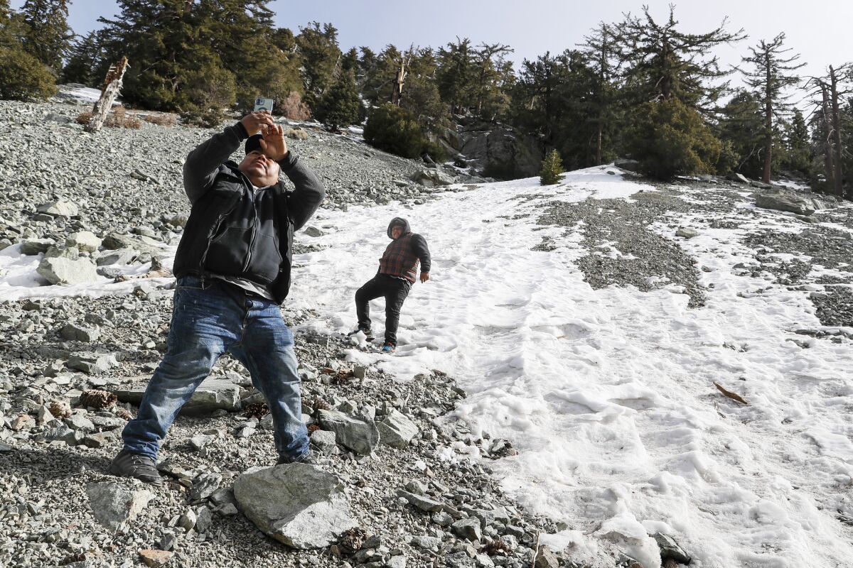 A man takes a selfie with a child playing in snow
