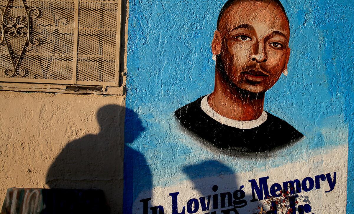 Passersby pause at a memorial to Ezell Ford, who was shot and killed by the LAPD last summer.
