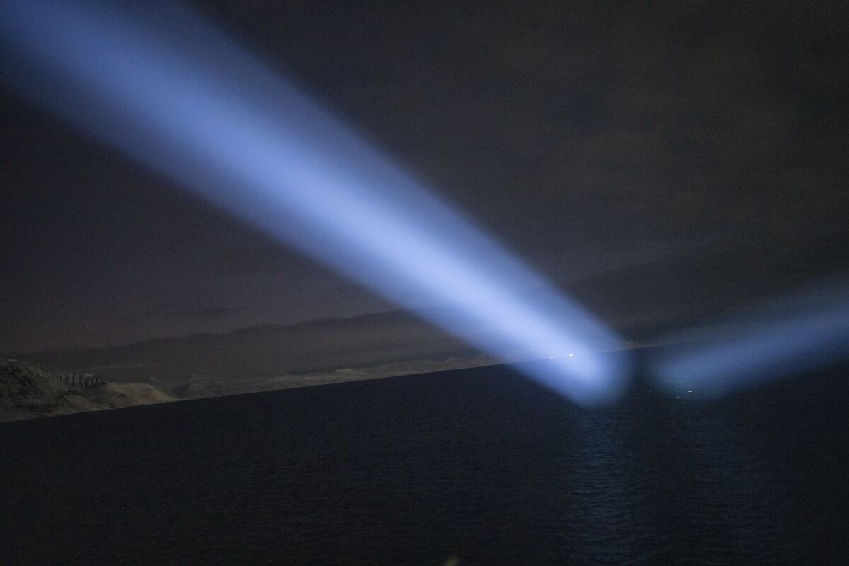 Spotlights from the governor's boat light the horizon during a journey from Longyearbyen to Barentsburg, Norway, Saturday, Jan. 7, 2023. It was carrying the children's choir from Longyearbyen's only church, Svalbard Kirke, to visit the even more isolated Arctic outpost of Barentsburg, which is run by a Russian mining company. (AP Photo/Daniel Cole)