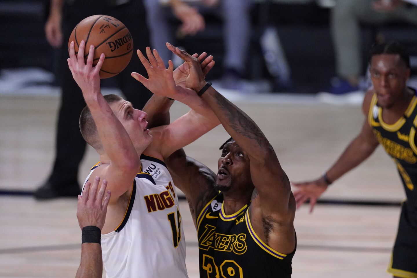 Nuggets center Nikola Jokic attempts a shot over Lakers center Dwight Howard.
