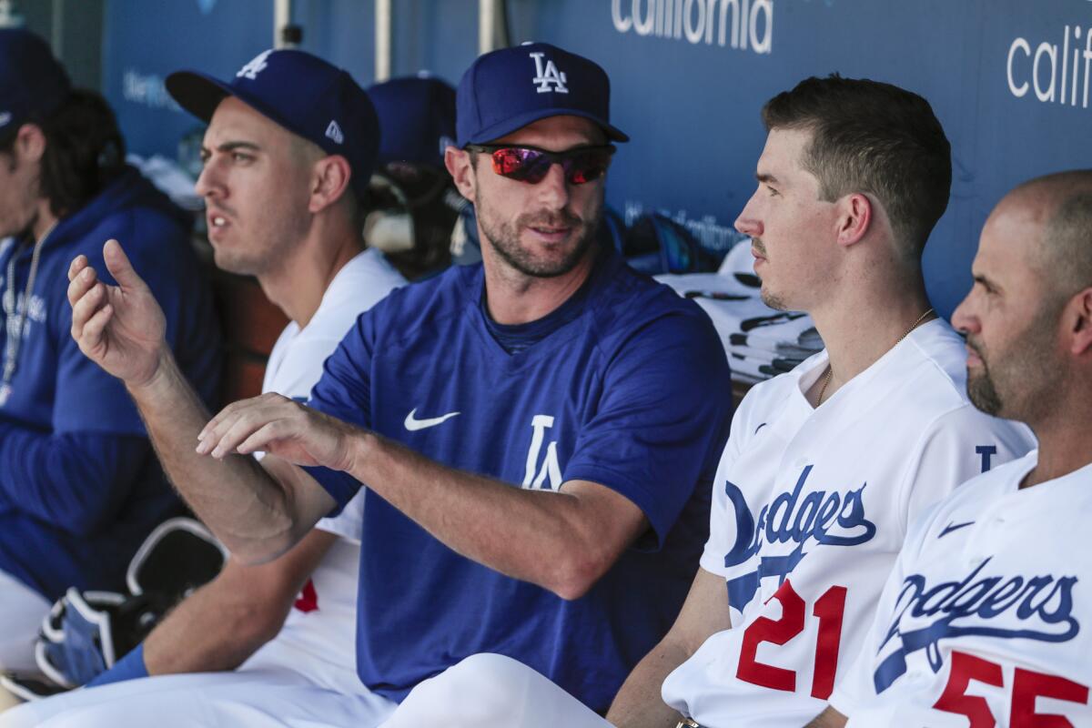 Dodgers pitcher Walker Buehler (21) speaks with pitcher Max Scherzer in the dugout.