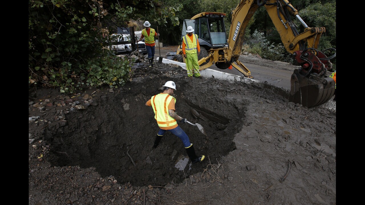 Orange County public works crews use shovels and heavy equipment along Silverado Canyon Road after heavy rains sent torrents of mud, dirt and rocks onto the roadway and clogged storm drains in the area Tuesday.