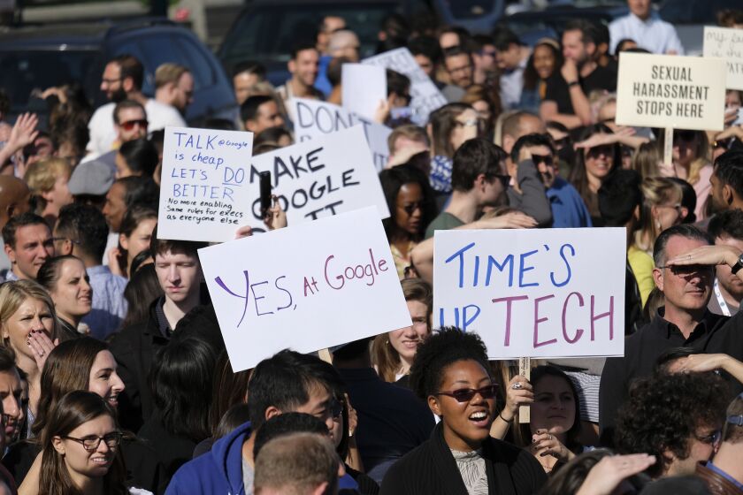 Google employees hold up signs at Harry Bridges Plaza during a walkout Thursday, Nov. 1, 2018, in San Francisco. Several thousand Google employees around the world briefly walked off the job Thursday in a protest against what they said is the tech company's mishandling of sexual misconduct allegations against executives.