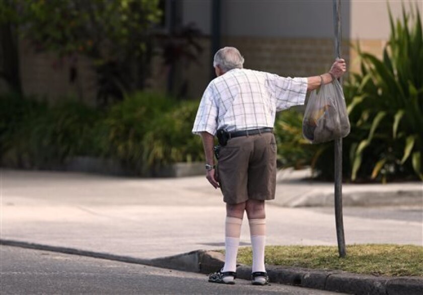 In this Friday, Oct. 11, 2013 photo, an elderly man holds onto a signpost on the side of a road in Sydney. About a third of people over 65 fall every year, according to the World Health Organization. (AP Photo/Rick Rycroft)