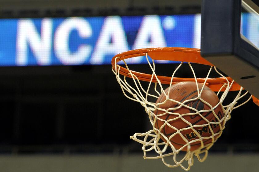 FILE - In this March 20, 2010, file photo, a ball flicks through the net in front of the NCAA logo on the marquis during an NCAA college basketball practice in Pittsburgh. Defying the NCAA, California's governor signed a first-in-the-nation law Monday, Sept. 30, that will let college athletes hire agents and make money from endorsements — a move that could upend amateur sports in the U.S. and trigger a legal challenge. (AP Photo/Keith Srakocic, File)