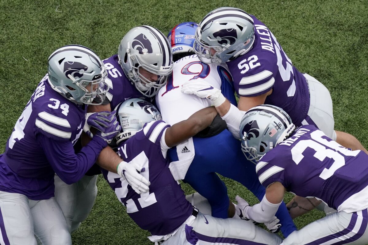 FILE - In this Oct. 24, 2020, file photo, Kansas wide receiver Steven McBride (19) is tackled by a group of Kansas State defenders during the second half of an NCAA football game in Manhattan, Kan. The Big 12 will have nothing like the Red River rivalry on the second Saturday in October once Texas and Oklahoma make their move to the Southeastern Conference. There will even be the renewal of some old but not as long standing feuds, and maybe some new ones when BYU, Central Florida, Cincinnati and Houston begin Big 12 play within the next two to three seasons. (AP Photo/Charlie Riedel, File)