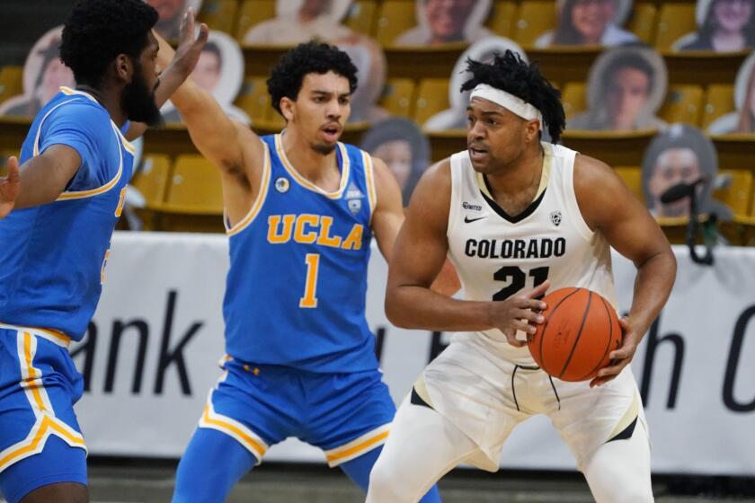 Colorado forward Evan Battey, right, is trapped with the ball by UCLA guard Jules Bernard.