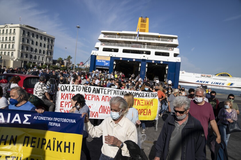 Protesters hold placards as they leave from the port of Piraeus port, near Athens, on Thursday, June 3, 2021. Ferry services to the Greek islands were disrupted Thursday morning after a seamen's union went ahead with a strike that a court had declared illegal.(AP Photo/Petros Giannakouris)