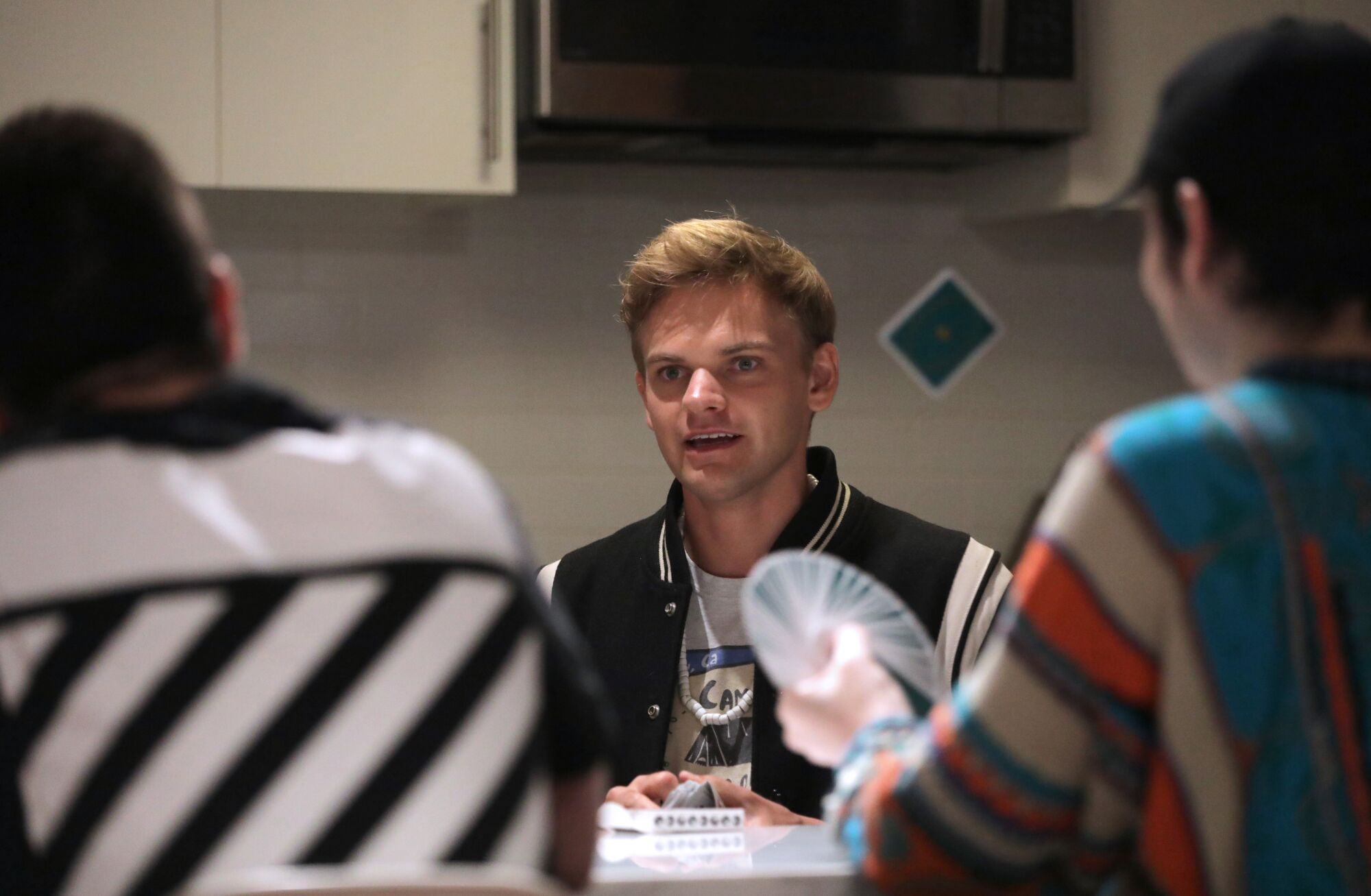 Three men with cards at a table.