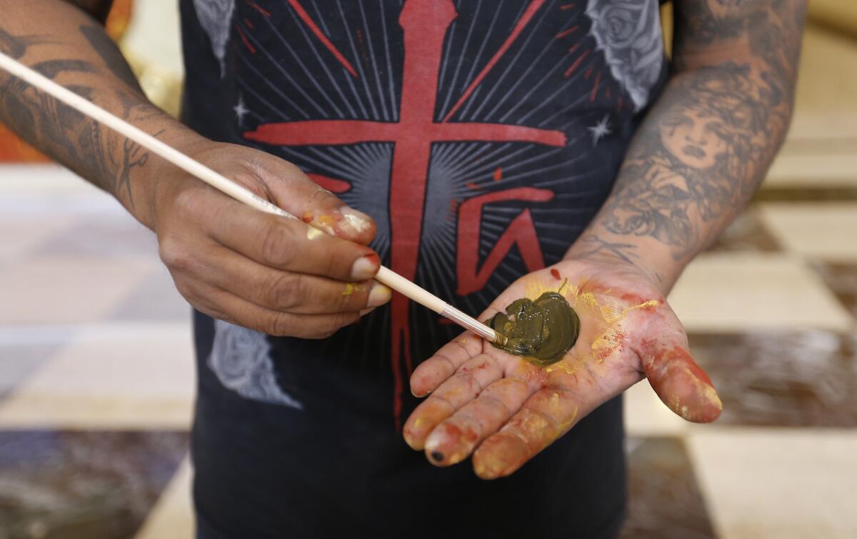 Canul and his palette. The murals will be on view through Jan. 31. (Al Seib / Los Angeles Times)