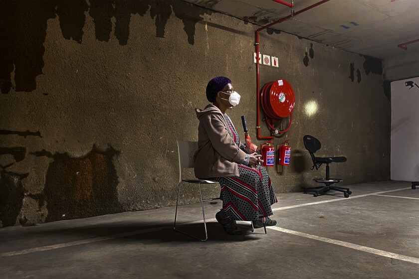 A lone woman waits to be tested for COVID-19 in the parking garage of a shopping mall in Johannesburg, South Africa, Monday Jan. 11, 2021. South Africa is struggling to cope with a spike in COVID-19 cases that has already overwhelmed some hospitals, as people returning from widespread holiday travel speed the country's more infectious coronavirus variant. (AP Photo/Jerome Delay)