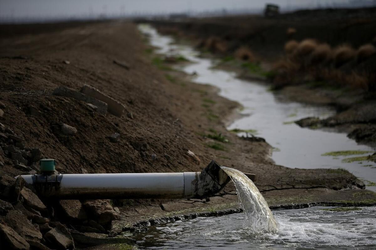 Water is seen last month pouring into an irrigation channel in Firebaugh, Calif.