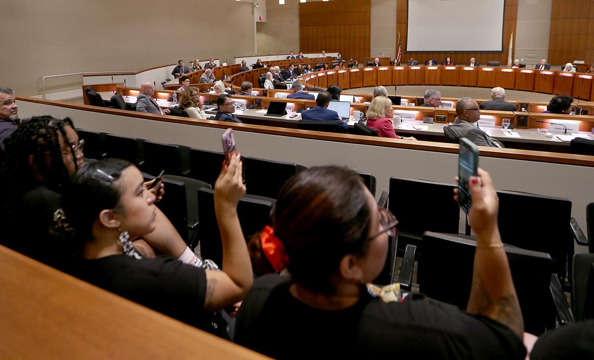 Students hold up their phones during a CSU Board of Trustees meeting.