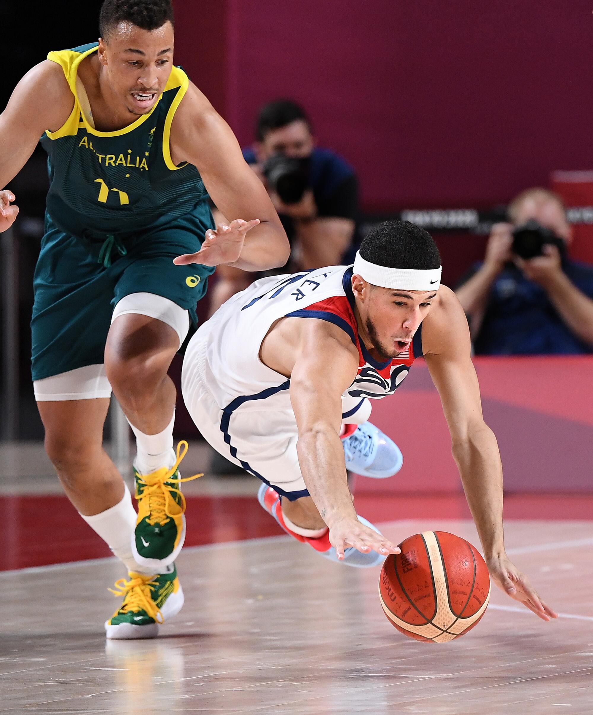 Devin Booker dives for the basketball in front of Australia’s Dante Exum at the Tokyo Olympics.