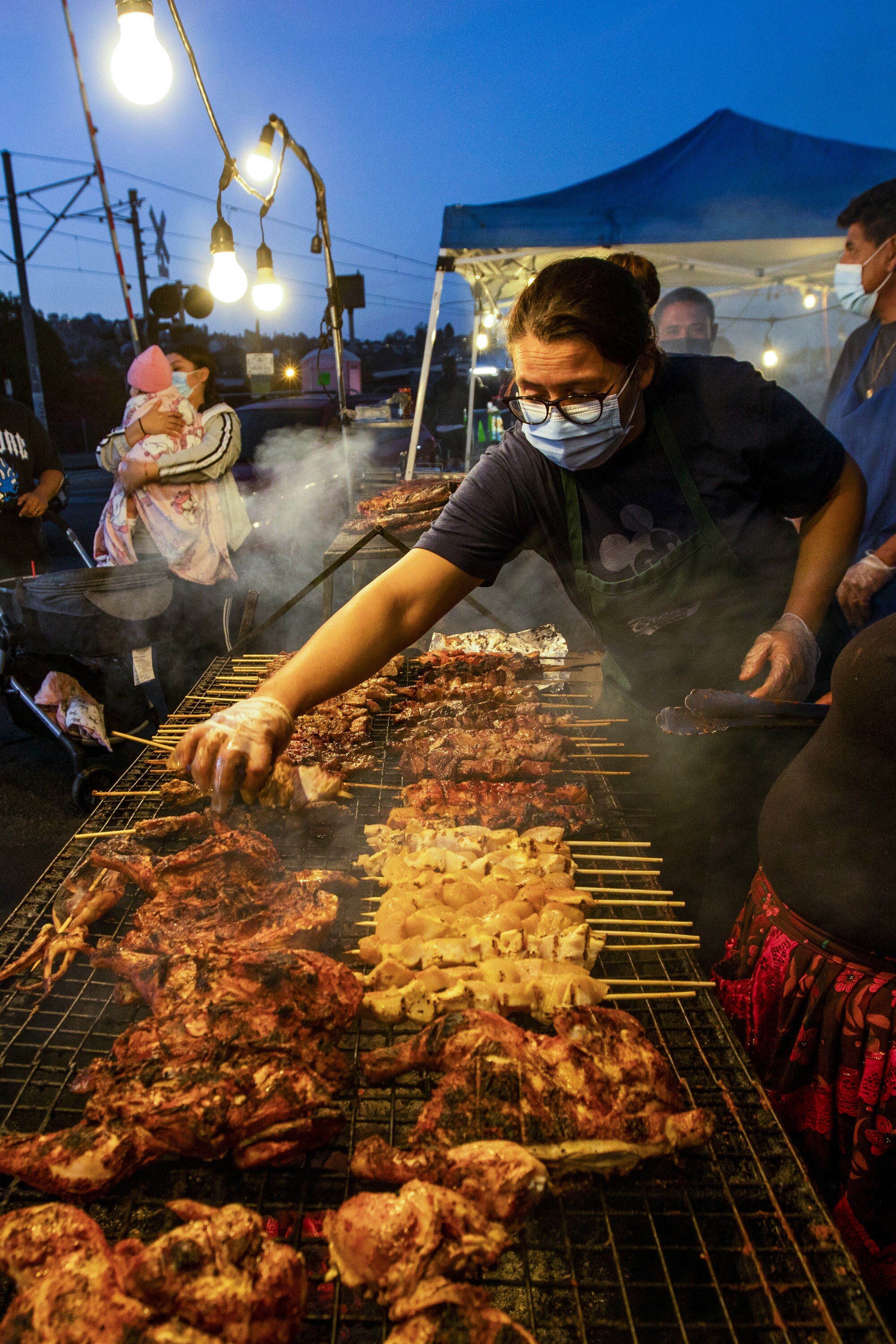 A woman grills skewers of meat