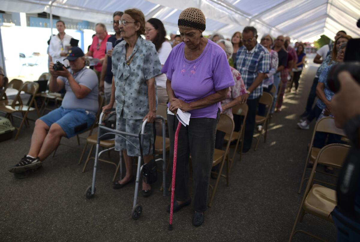 People attend an outdoor Mass on Saturday under a tent set up near the Immaculate Conception Catholic Church in Guanica, Puerto Rico, after a magnitude 5.9 quake earlier in the day.