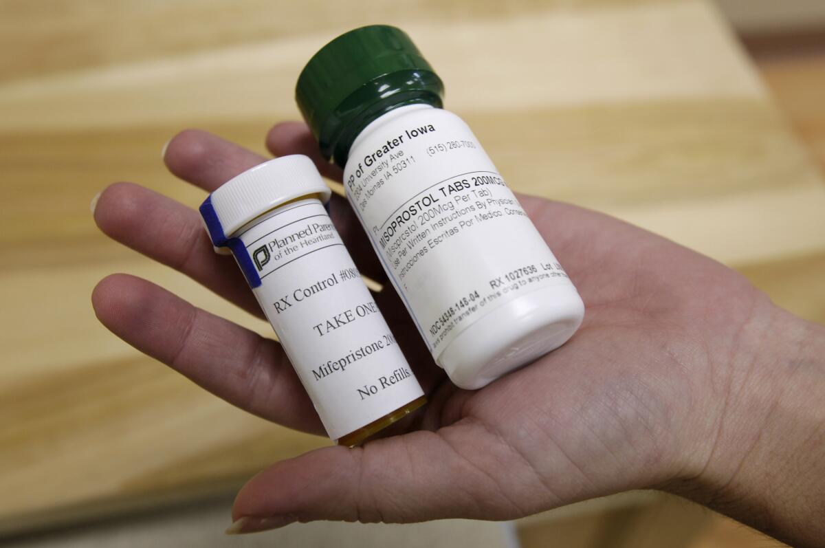 Two medication bottles are held in a person's hand