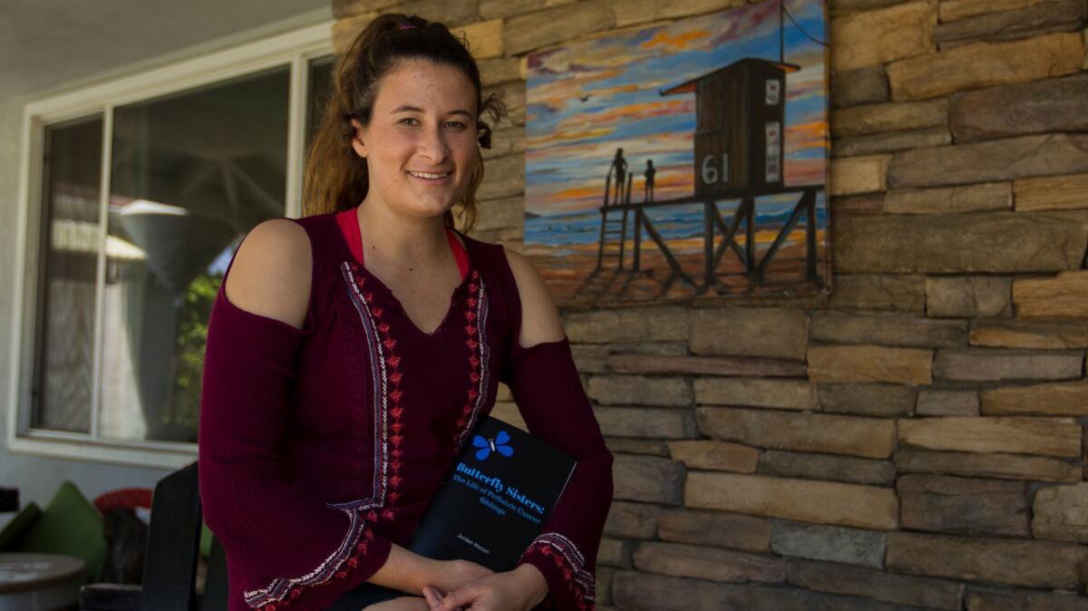 Jordan Wetzel, a senior at Edison High School, with her book about losing her sister, Mckenna Claire, 7, titled "Butterfly Sisters: The Life of Pediatric Cancer Siblings."