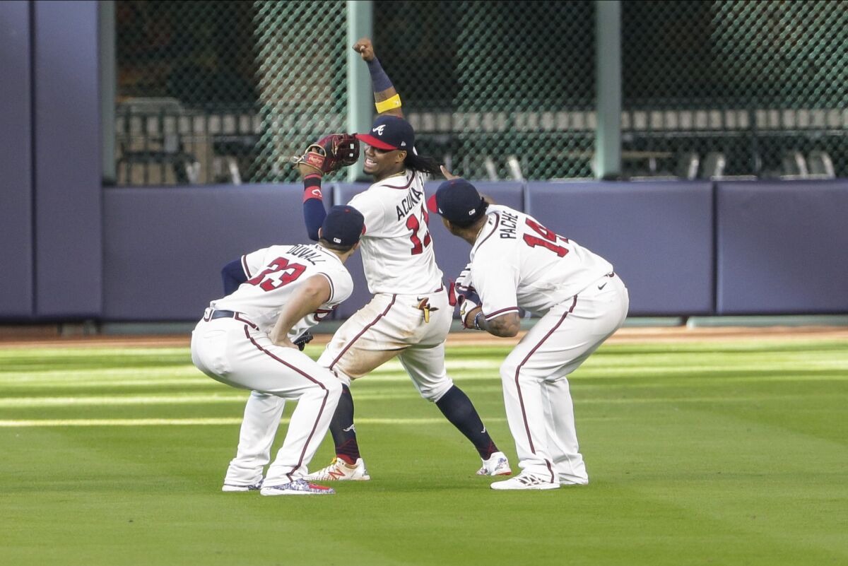 Atlanta Braves' Ronald Acuna Jr., center, celebrates with teammates Adam Duvall, left, and Cristian Pache, right, after Game 1 of a baseball National League Division Series against the Miami Marlins Tuesday, Oct. 6, 2020, in Houston. (AP Photo/Michael Wyke)