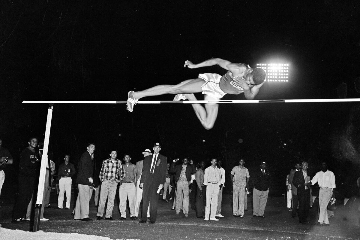 Charles Dumas soars to a world record with a leap over 7 feet during men's high jump competition.