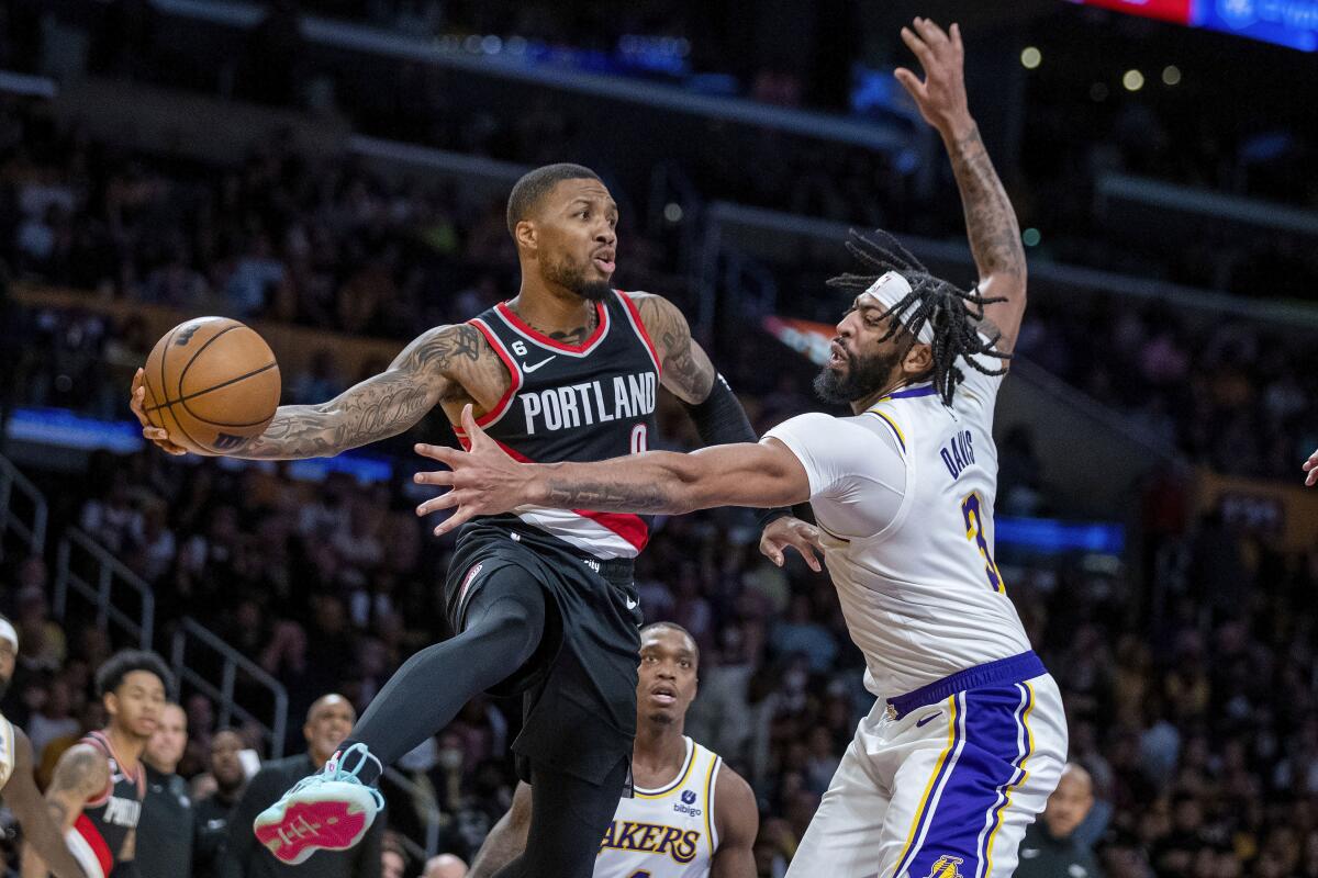 Trail Blazers guard Damian Lillard leaps along the baseline to make a pass around Lakers forward Anthony Davis.