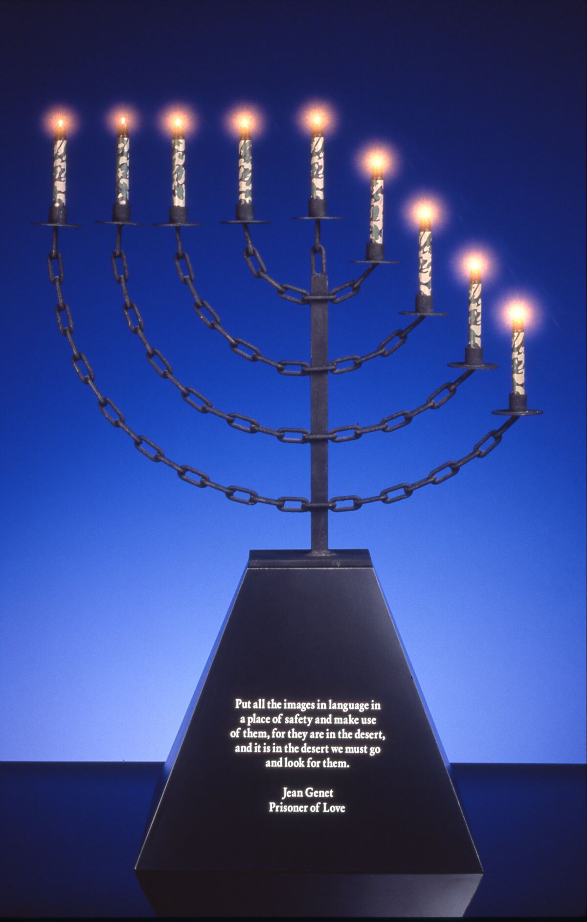 John Boskovich, “Bondage Menorah,” 1997. Metal, black formica base with Jean Genet text, U.S. issue camouflage Mini-Maglites, 41.5 inches by 30 inches by 16.5 inches