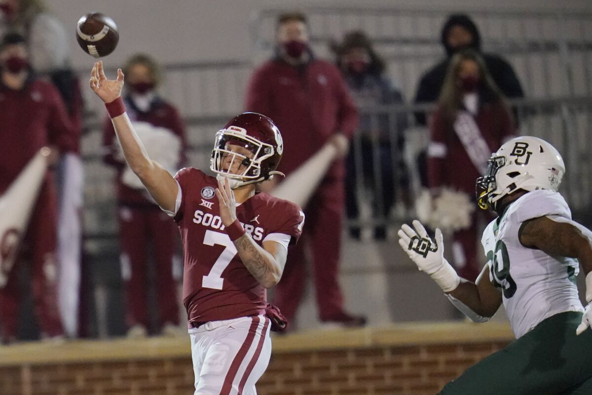 Oklahoma quarterback Spencer Rattler (7) passes under pressure from Baylor linebacker William Bradley-King (99) in the first half of an NCAA college football game Saturday, Dec. 5, 2020, in Norman, Okla. (AP Photo/Sue Ogrocki)