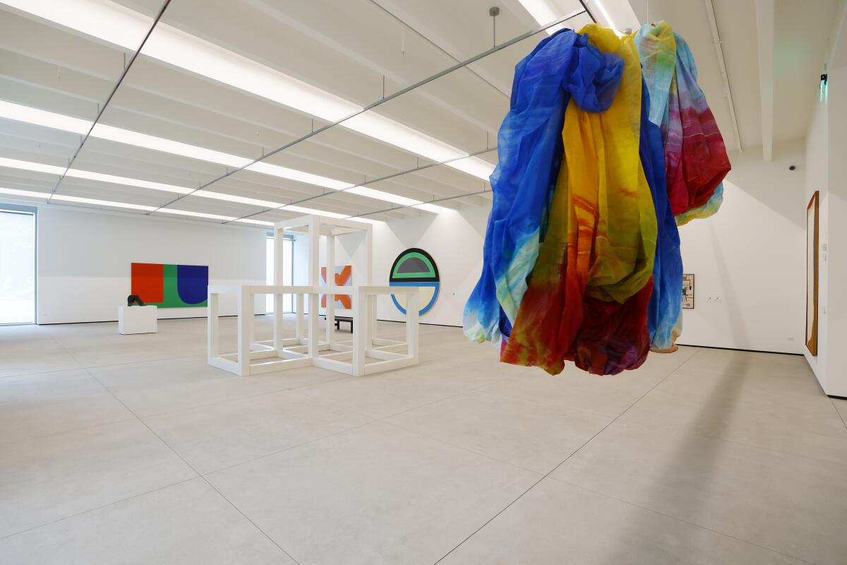 A sculpture of white cubes and colorful fabric art and paintings in a gallery at the Museum of Contemporary Art San Diego.