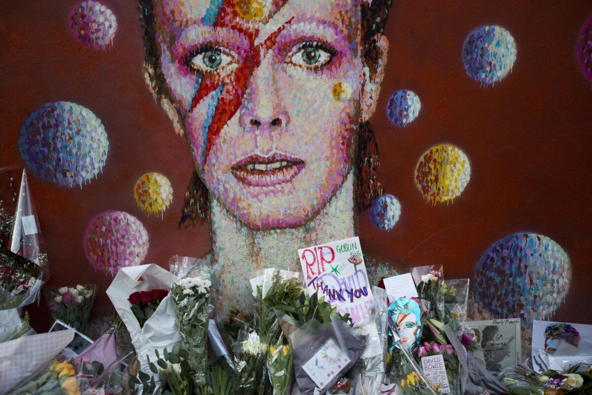 En esta foto del 12 de enero del 2016, homenajes para David Bowie colocados por fans junto a un mural del cantante realizado por el artista Jimmy C en Brixton, en el sur de Londres. Bowie, un músico que traspasó las fronteras del pop y el rock con su creatividad y un personaje andrógino al que llamó Ziggy Stardust, murió el 10 de enero del 2016 a los 69 años.