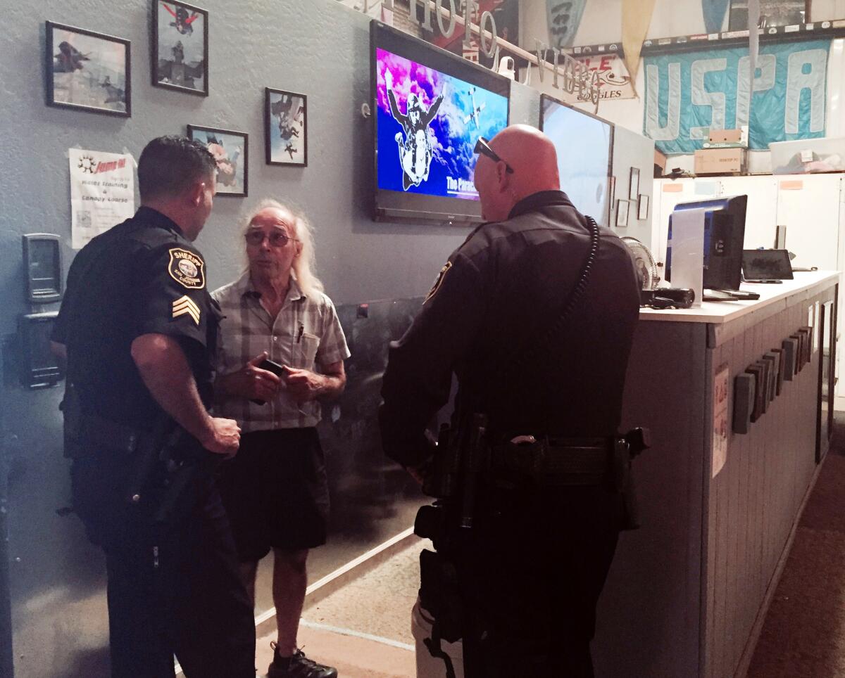 Sheriff's deputies talk with a man in an office.