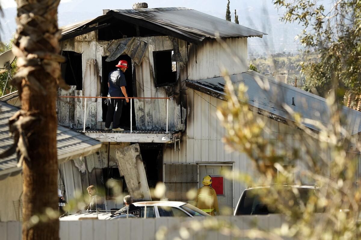 Los Angeles Fire Department arson investigators inspect the first and second floor of a two-story metal-clad, barn-like home in the 13700 block of Eldridge Avenue in Sylmar on Jan. 13, where four people were pulled from the burning home.