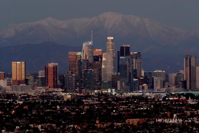 LOS ANGELES, CALIF. - FEB. 23, 2022. Snow covers Mt. Baldy behind the Los Angeles skyline on Wednesday, Feb. 23, 2022. Cold weather is expected to give way to a warming trend next week. (Luis Sinco / Los Angeles Times)