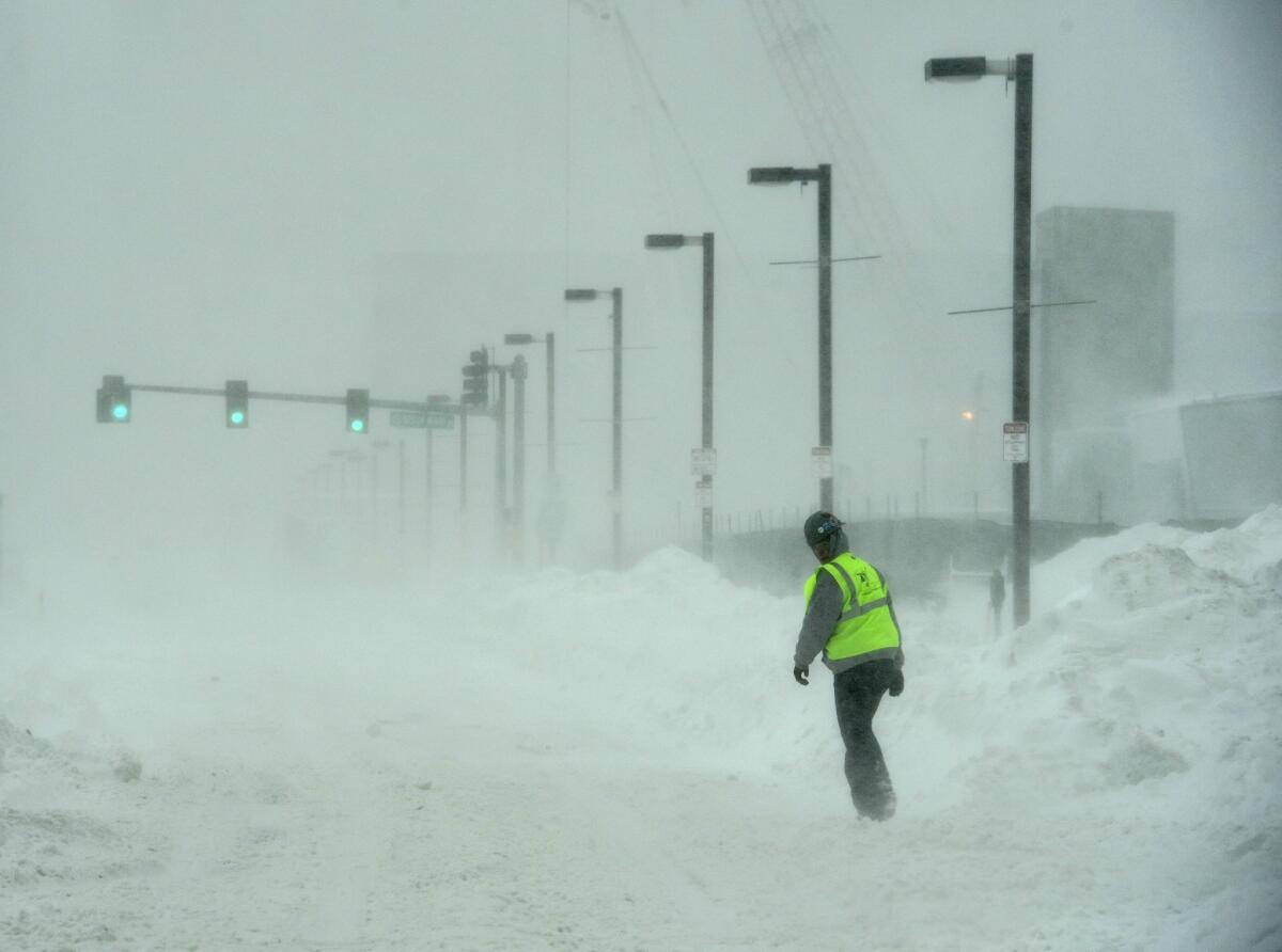 A construction worker walks in the blowing snow along Seaport Boulevard in Boston on Monday.