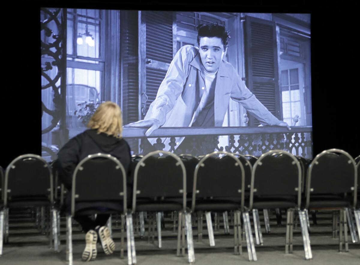 A woman watches the Elvis Presley film "King Creole" in a theater in the "Elvis Presley's Memphis" complex.
